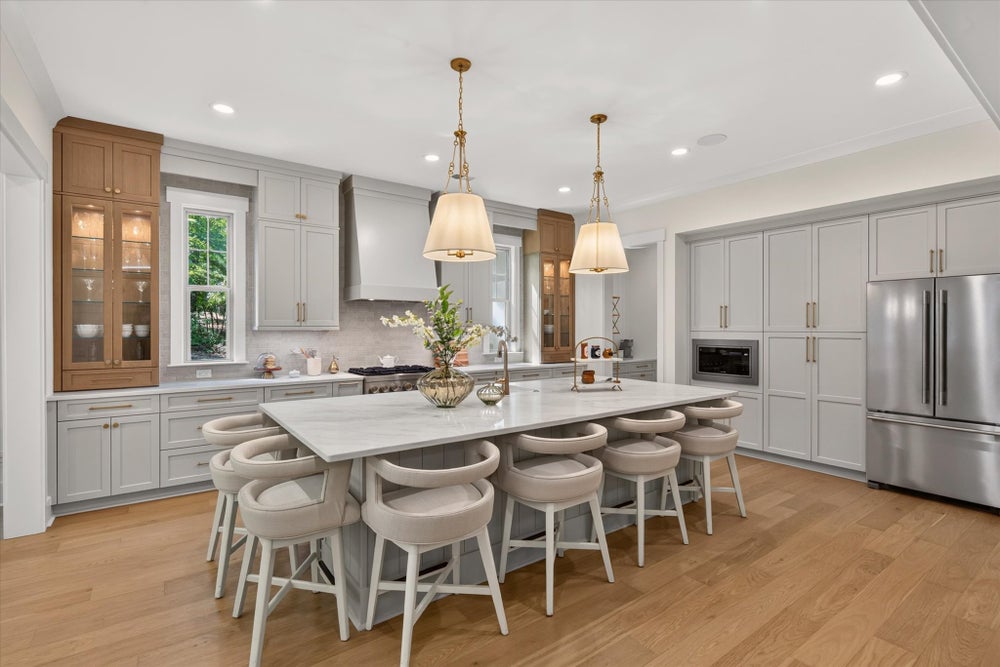 Large kitchen with gray cabinets, oversized island with seating, pendant lights, and hardwood floors