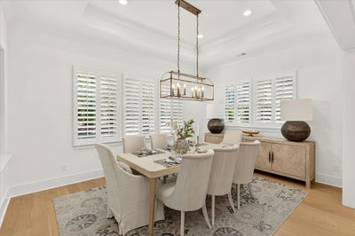 Dining room with six-chair table, brass chandelier, plantation shutters, and wood sideboard on patterned rug