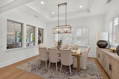 Formal dining room with eight-seat table, coffered ceiling, bronze chandelier, and hardwood floors