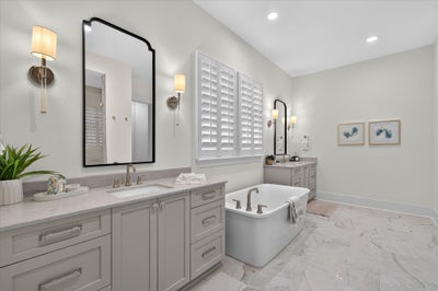 Master bathroom with dual vanity, freestanding soaking tub, and marble tile floors