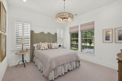 Bedroom with wood headboard, plantation shutters, pendant light, and carpet flooring