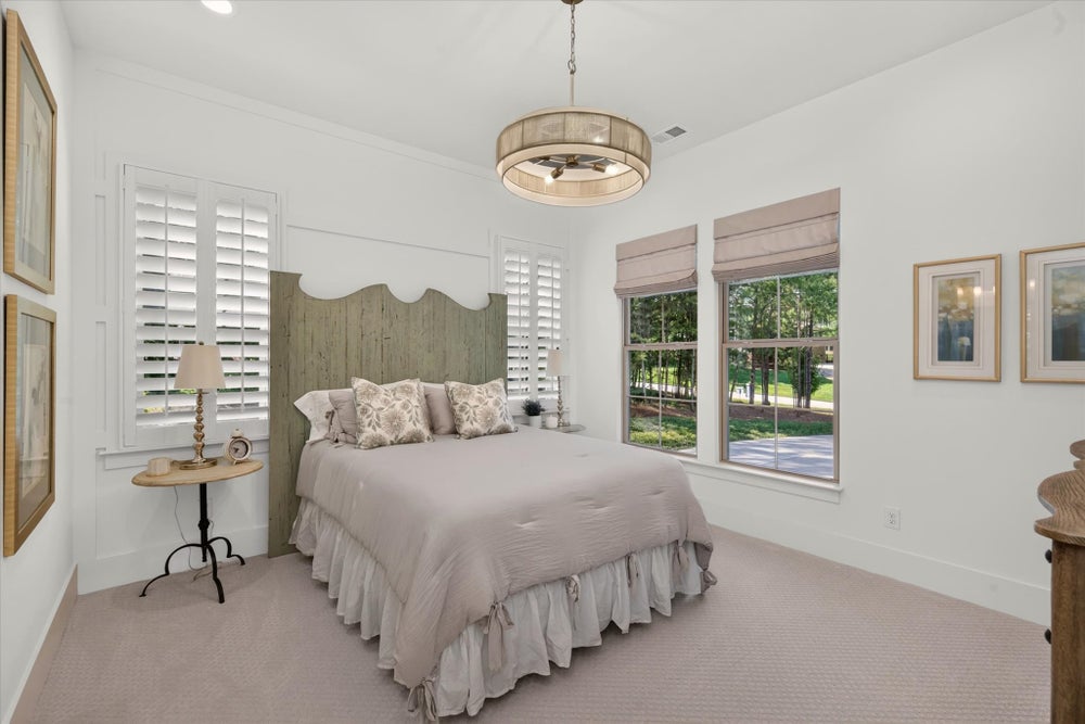 Bedroom with wood headboard, plantation shutters, pendant light, and carpet flooring