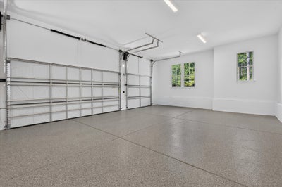 Spacious two-car garage with epoxy floor, white walls, and two windows