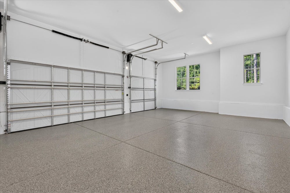 Spacious two-car garage with epoxy floor, white walls, and two windows