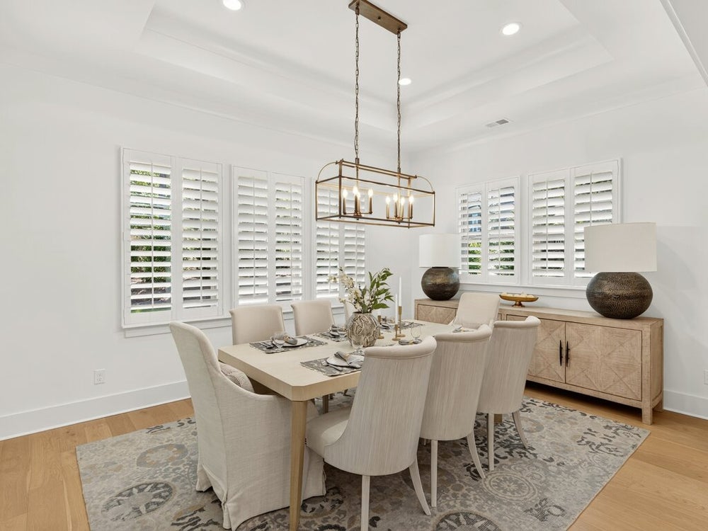 Dining room with six-seat table, brass chandelier, plantation shutters, and hardwood floors