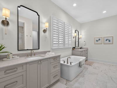 Master bathroom with dual vanities, freestanding soaking tub, and marble tile floors