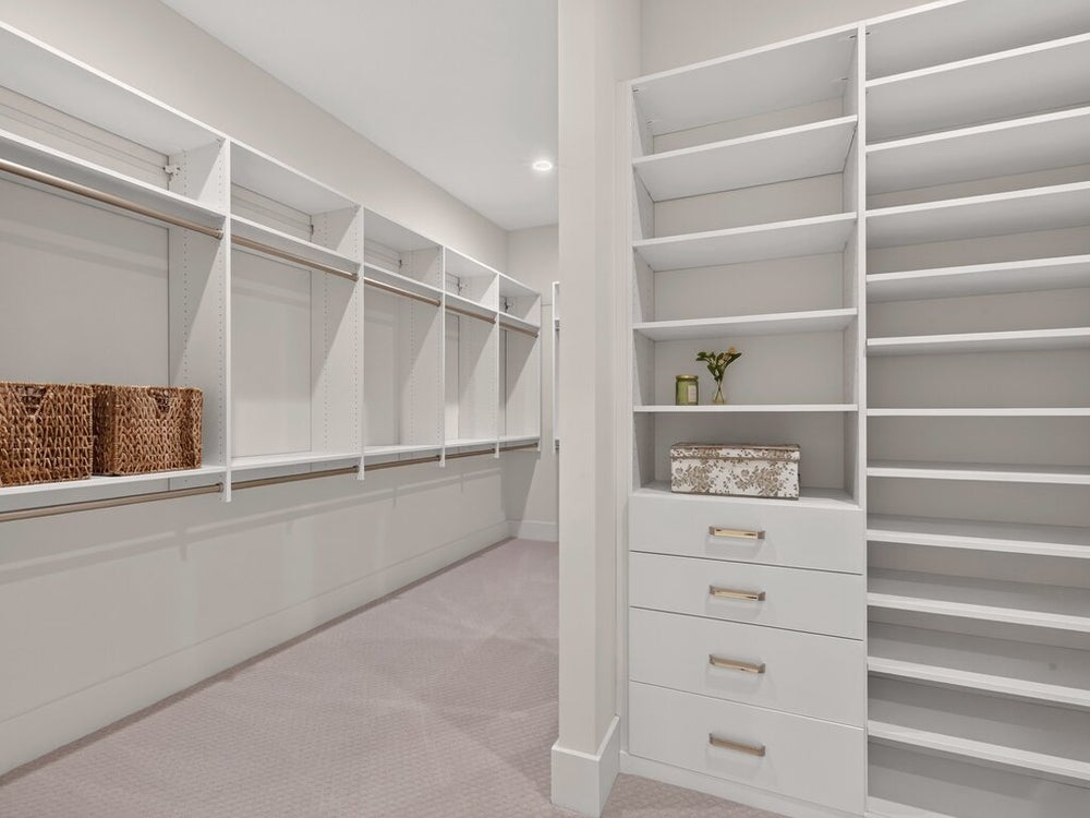 Walk-in closet with white built-in shelving, hanging rods, drawers, and carpeted floors