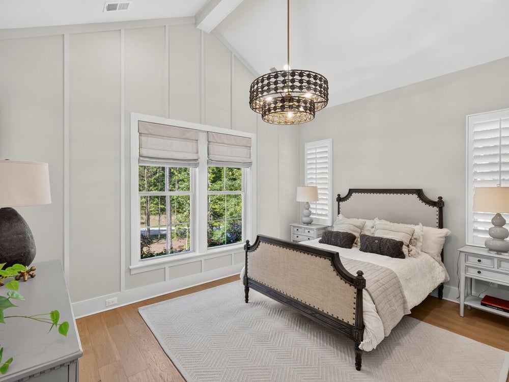 Bedroom with vaulted ceiling, wood floors, dark wood bed frame, and decorative chandelier