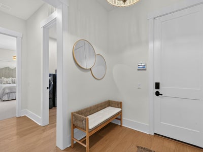 Entryway with wood bench, round wall mirrors, white front door, and hardwood floors