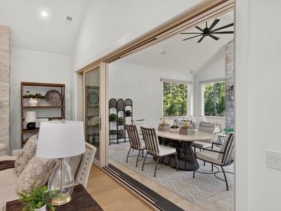 Living room with large sliding glass doors opening to a sunroom with dining table and ceiling fan