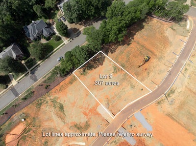 Aerial view of Lot 9, a 0.307-acre cleared residential building lot beside a curved road and neighboring homes.