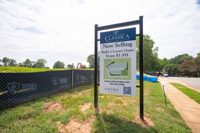Classica Homes new development sign for Enclave at Carrington, advertising luxury homes from $1.8M, with active construction site behind fencing.